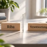 Zwei Holzklötze mit den Aufschriften „Riba“ und „Verantwortung“, getrennt durch eine Glasscheibe, daneben Bücher zu Wirtschaft, Gesellschaft und Perspektiven – Sinnbild für Begriffsklärung und Grenzziehung.